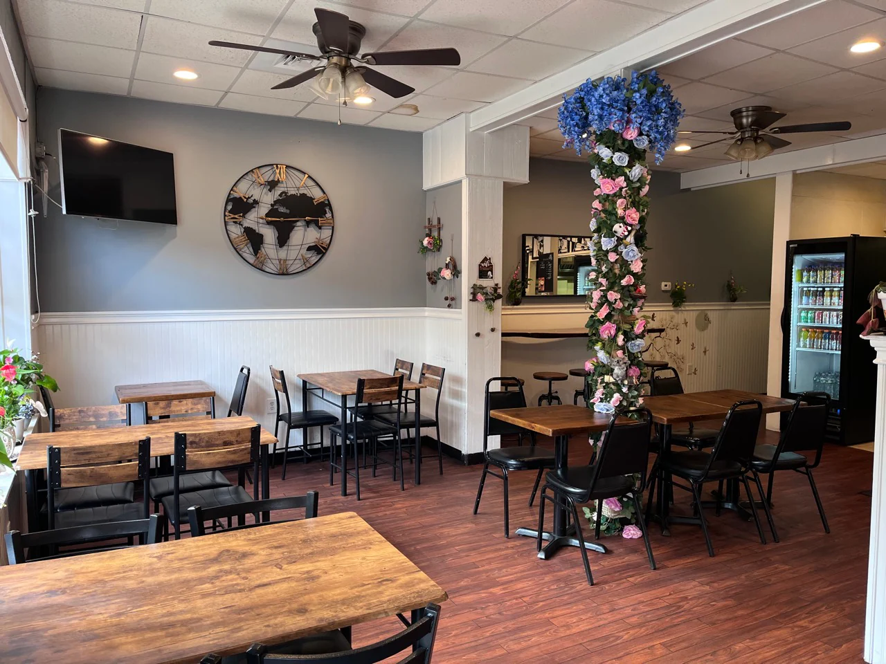 Funcle’s Café dining area with wooden tables, black chairs, and floral decor.
